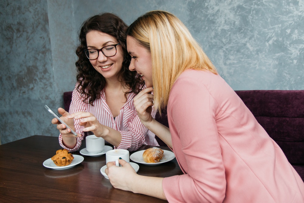 Women Smiling While Looking At Phone
